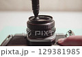 Professional photographer gently cleaning vintage camera lens, using specialized lens pen 129381985
