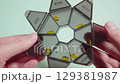 Rotating transparent pill organizer, revealing yellow capsules sorted in labeled daily compartments with weekday abbreviations 129381987