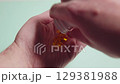 Omega 3 fish oil capsules pouring from a white plastic bottle onto an open hand on a light green background 129381988