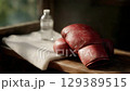 Boxing gloves resting on bench beside water bottle and towel. 129389515
