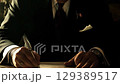 Bank executive signing documents, piles of cash on the desk. 129389517