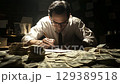 Bank executive signing documents, piles of cash on the desk. 129389518