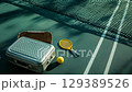 A silver suitcase with a pickleball paddle and wicker baskets standing at a tennis court. 129389526