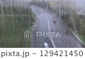 View of the road through a wet window with drops, during the rain with the reflection of people 129421450
