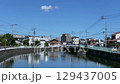 青空の下で静かに流れる町の川 129437005