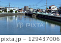 青空の下で静かに流れる町の川 129437006