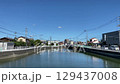 青空の下で静かに流れる町の川 129437008