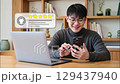 A young man happily giving a five-star rating on his smartphone, representing customer satisfaction and success 129437940