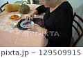 An elderly woman sorts dried barberries. A grandmother prepares food at the table in the kitchen. Dry berry. 129509915