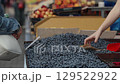 Buying blueberries at the market. A woman buys berries at a local market. The customer pays in cash. A seller gives a buyer a bag of berries. 129522922
