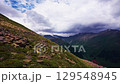 Mountain slope with rocky terrain under dramatic clouds 129548945