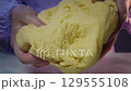 Kneading dough, closeup of hands shaping soft yellow pastry on marble surface 129555108