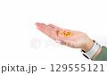 Outstretched hand offering golden capsules amidst white space 129555121