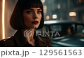 A close-up view captures a fashionable woman with a bold bob haircut and striking makeup, moving through a hazy urban environment at night with blurred vehicle lights. 129561563