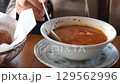 Person eating soup on a table  129562996