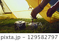 Woman mini portable gas stove, pot from tent. Solo camping, cooking outdoors. Ultralight gear for backpacking, self-reliant living in wilderness. Preparing meal, boiling water. Slow motion. 129582797