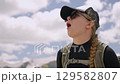 Hiker woman enjoys panoramic view of Svaneti mountains. Wearing backpack and hat, she admires the scenic Greater Caucasus Mountain Range under cloudy sky during daytime Slow motion. 129582807