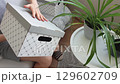 Slow motion footage of the woman sitting in the couch in cozy room, assembling carton boxes. Household 129602709