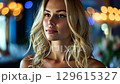 In a trendy restaurant, a blonde woman with wavy hair is seen smiling and talking with friends under warm, ambient lighting. The setting is filled with vibrant decorations and a relaxed vibe. 129615327