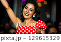 Captivating summer travel experience featuring a stylish figure in red dress with polka dot design. Exciting energy fills the venue as she dances with grace, enjoying moments of joy and celebration. 129615329