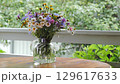 Bouquet of wild flowers in a glass vase on a wooden table 129617633