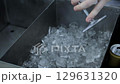 A bartender puts ice in a glass to make a cocktail, slow motion, close-up 129631320