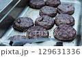 Beef burger patties with cheese in a tray on the table, close-up. Slow motion 129631336