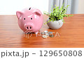 Image of a piggy bank and coins on a desk 129650808