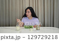 A woman is eating a salad with a fork 129729218