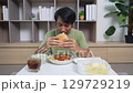 A man is eating a burger and drinking a soda 129729219