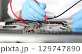 Gloved hands, on table repair an electronic device 129747890