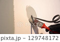 A black electric power wire is sticking out of the wall. Painting the walls with a brush around the wire. Apartment renovation. High quality 4k footage 129748172
