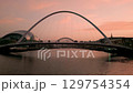 NEWCASTLE/UK 6th SEPTEMBER 2023: Drone rises in front of Millennium Bridge in Gateshead to reveal River Tyne and Tyne Bridge. Shot in summer twilight  129754354