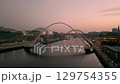 NEWCASTLE/UK 6th SEPTEMBER 2023: Drone tracks around Millennium Bridge Newcastle with Sage Centre and Tyne Bridge in background. Shot in evening twilight. A boat passes under bridge  129754355