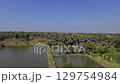 A serene panoramic view of a palmyra tree lined fish pond, with a small hut at the edge, under a clear blue sky. Located in Gresik, East Java. Indonesia. 129754984