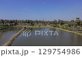 A serene panoramic view of a palmyra tree lined fish pond, with a small hut at the edge, under a clear blue sky. Located in Gresik, East Java. Indonesia. 129754986