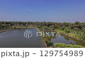 A serene panoramic view of a palmyra tree lined fish pond, with a small hut at the edge, under a clear blue sky. Located in Gresik, East Java. Indonesia. 129754989