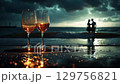 Two glasses of sparkling wine against a dramatic landscape with a romantic atmosphere.  Two glasses of sparkling wine stand on the wet sand, reflecting the warm light, gently washed by the waves. 129756821