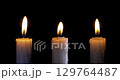 A set white candle burning. Isolated candle slow motion burning with dark background. White paraffin candle with yellow shades burns on a black background. Slow motion. 129764487