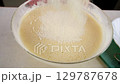 Baker adding mixing flour into batter with electric mixer cooking biscuit dough. 129787678