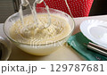 Baker mixing flour into batter with electric mixer cooking biscuit dough. 129787681