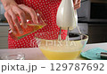 Pastry chef woman hands pouring vegetable oil into whisked eggs batter. 129787692