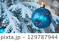 Blue Christmas baubles with a frosted finish hang from snow-covered pine branches in a serene winter scene. zoom in, zoom out, pan, or 360 degree shot, animate 129787944