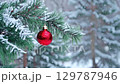 Red Christmas baubles hang on frosted branches with a soft blue background creating a festive winter atmosphere. zoom in, zoom out, pan, or 360 degree shot, animate 129787946
