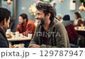 A positive homeless man sits at a table in a noisy homeless shelter cafeteria, surrounded by other people. Christmas concept. zoom in, zoom out, pan, or 360 degree shot, animate 129787947