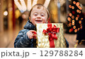Smiling child with down syndrome with Christmas gifts in shopping bags at the mall. Christmas sale concept. zoom in, zoom out, pan, or 360 degree shot, animate 129788284