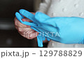 Female putting blue gloves for protection. Two hands wearing medical gloves close up. Personal protection. Sterile. 129788829