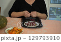 Old hands close up. An elderly woman sorts dried barberries. A grandmother prepares food at the table in the kitchen. 129793910