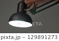 Hand turning off black desk lamp, close up of modern adjustable lighting 129891273