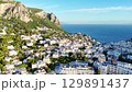 Picturesque coastal view of Capri Island showcasing vibrant homes and lush greenery under a radiant blue sky 129891437